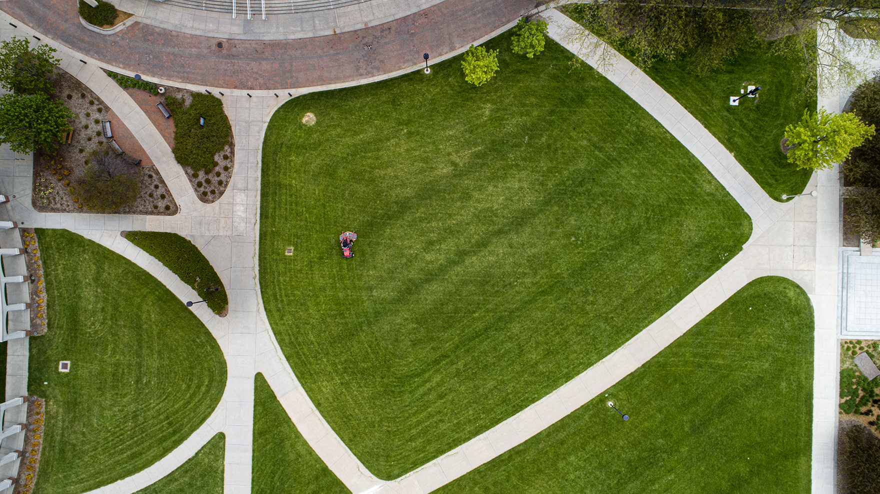 A Landscape Services employee mows the green space west of the Van Brunt Visitors Center. The university's landscape team has maintained momentum through the COVID-19 pandemic, observing health protocols while also maintaining campus grounds.