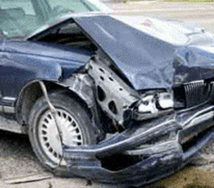 front of a blue car completely destroyed with hood bent upwards